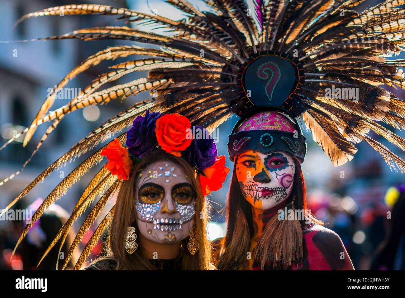 Ein mexikanisches Mädchen, bekleidet als La Catrina und mit einem Kopfschmuck aus aztekischen Federn, nimmt an den Feierlichkeiten zum Tag der Toten in Taxco, Mexiko, Teil. Stockfoto