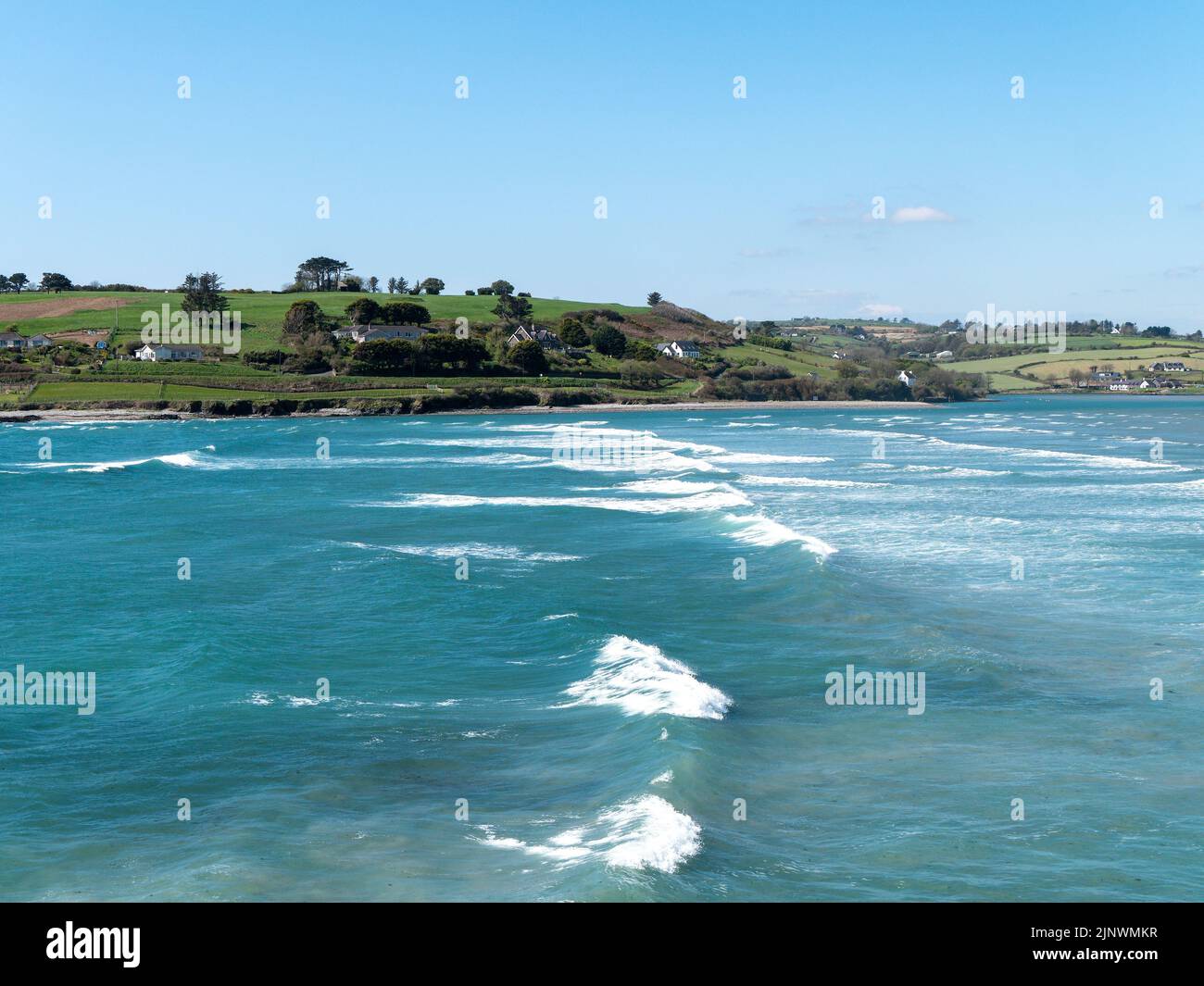 Malerische Bucht, sonniger Tag. Wunderschöne Natur im Süden Irlands. Blaues Wasser des Atlantischen Ozeans unter klarem Himmel. Küstenlandschaft. Meereswellen Stockfoto