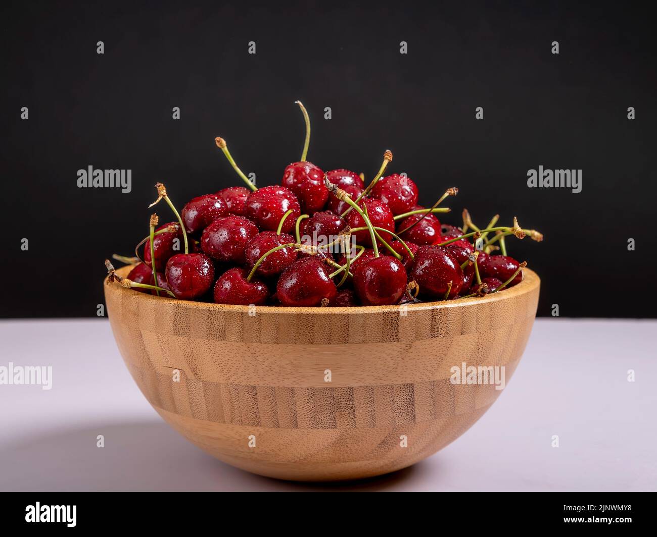 Eine Holzschale ist mit köstlichen roten Kirschen gefüllt Stockfoto