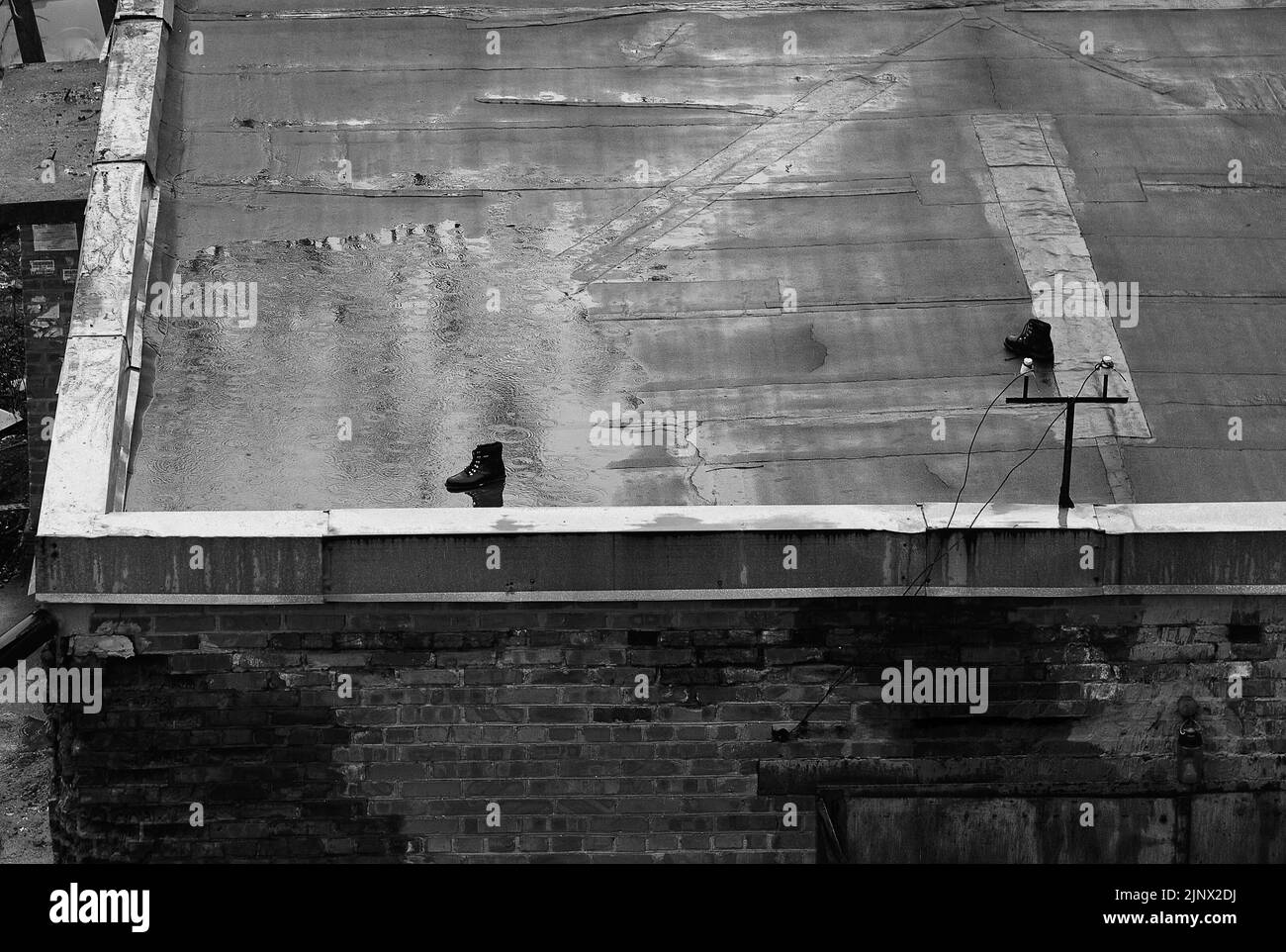 Urbane Szene: Alte vergessene Stiefel stehen auf dem Dach des Gebäudes. Regnerisches Wetter. Seltsames Konzept Stockfoto