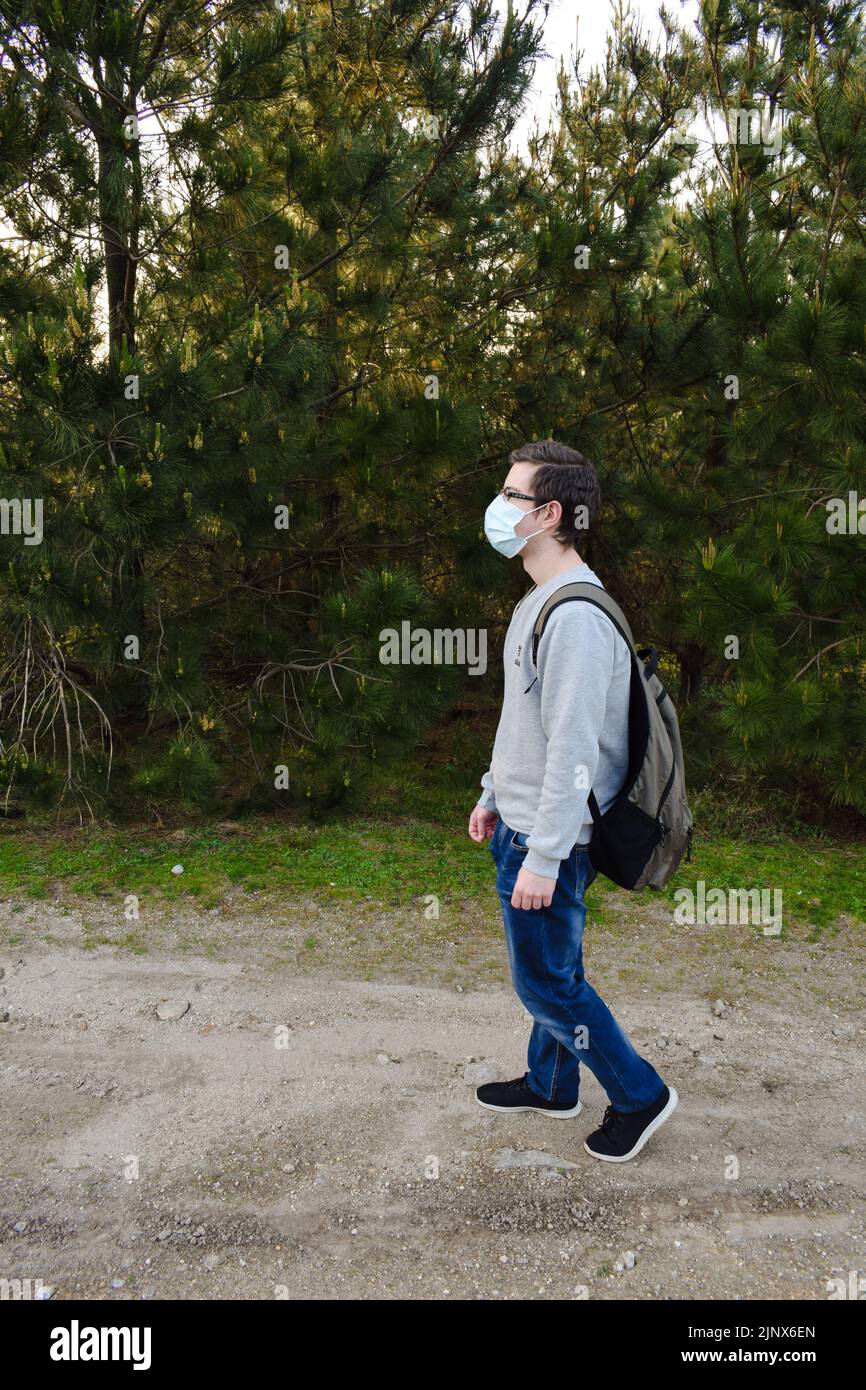 Junger Mann mit OP-Maske beim Spaziergang im Wald. Gesundheitskonzept Stockfoto