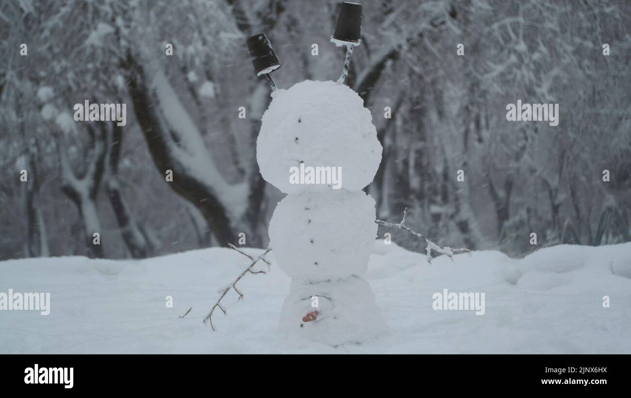 Fröhlicher lustiger Schneemann akrobatin auf dem Kopf, vor dem Hintergrund eines starken Schneefalls. Schneemann steht auf seinem Kopf Stockfoto