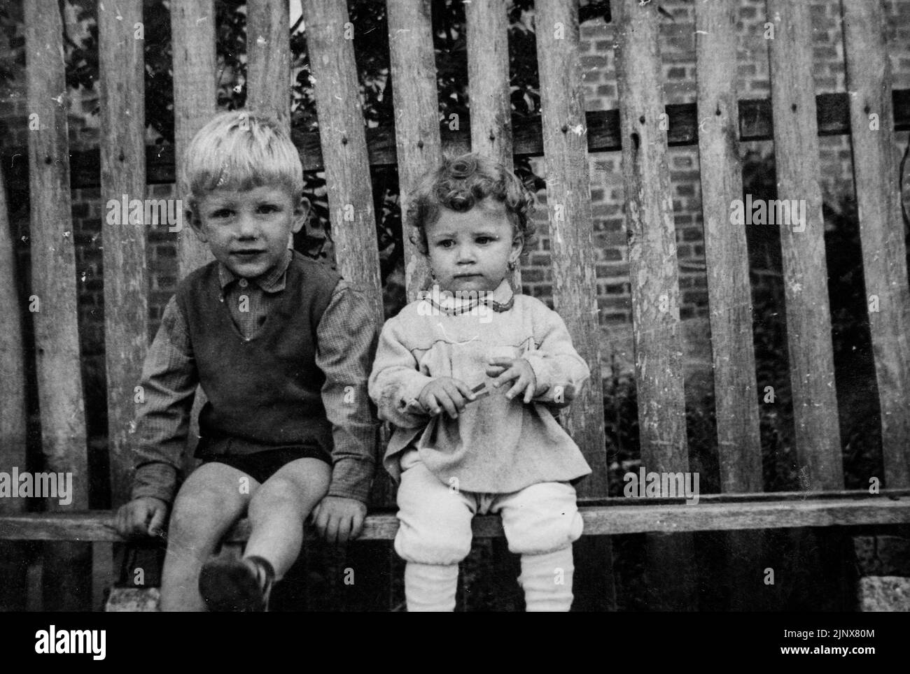 Zwei Geschwister Bruder und Schwester sitzen auf einer einfachen Holzbank 1970 ländliche Bulgarien Stockfoto