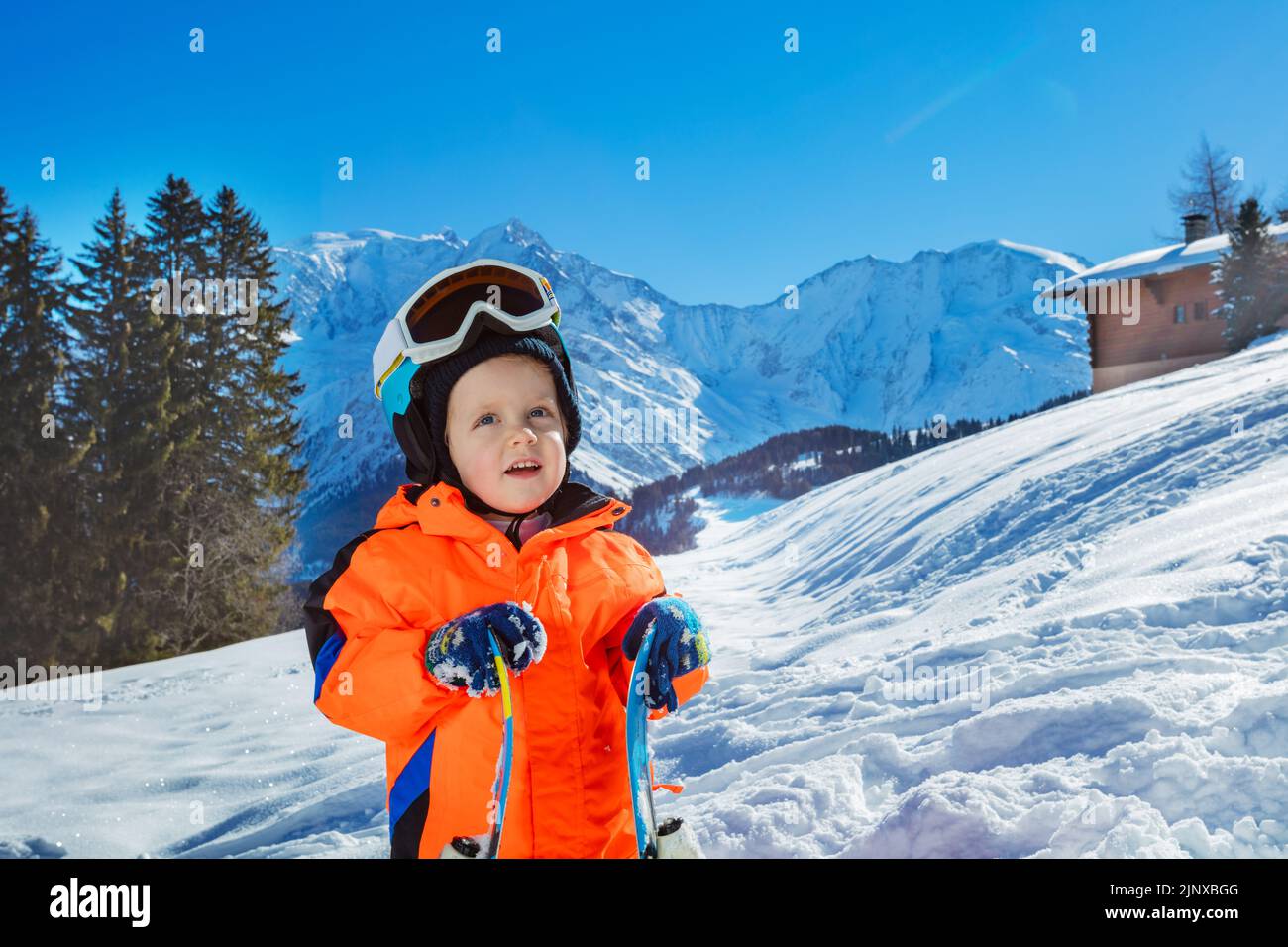 Junge 3 Jahre altes Kind mit Ski über Berge auf Hintergrund Stockfoto