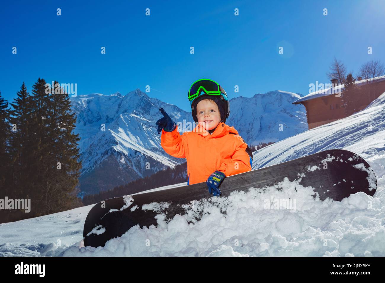 Snowboarder Boy zeigen mit dem Finger und lächeln auf der alpinen Skipiste Stockfoto