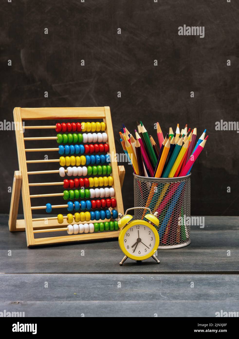 Zurück zur Schule. Bunte Stifte, Mathe Abacus und Wecker auf blauem Schreibtisch, Tafelhintergrund, Kopierraum Stockfoto