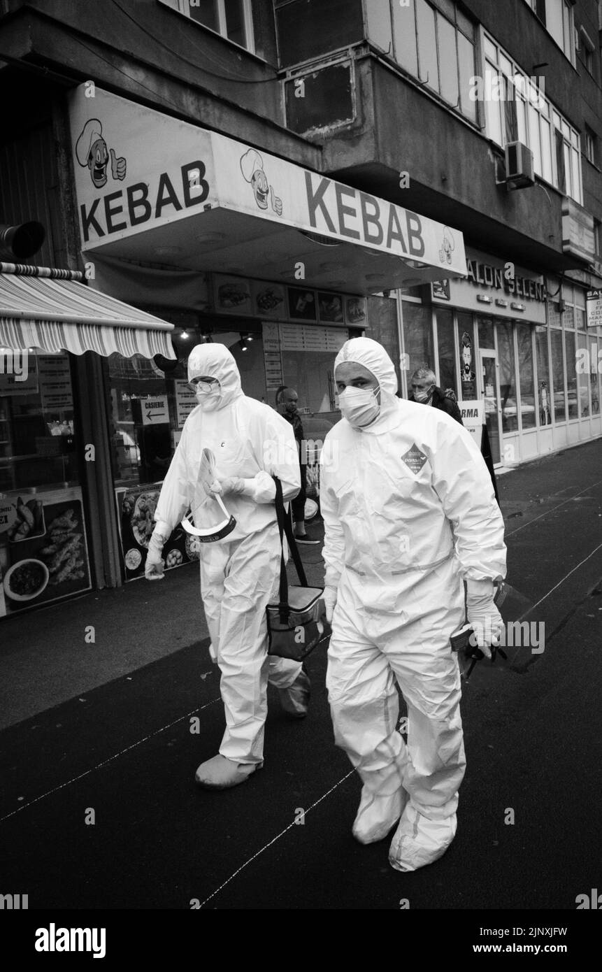 Zwei medizinische Fachkräfte betreuen einen COVID-Patienten in Bukarest vor einem Kebab-Shop Stockfoto