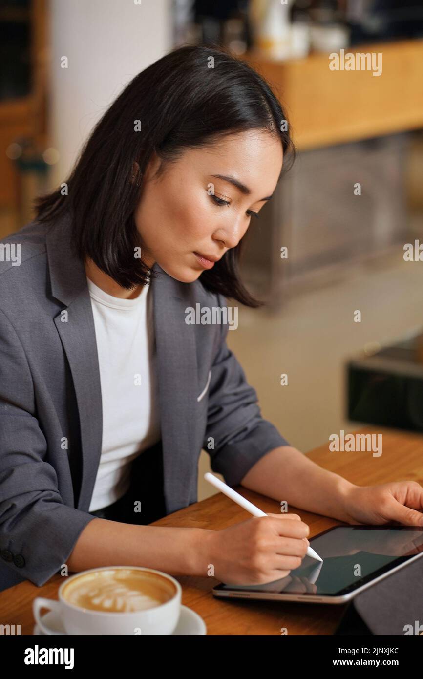 Beschäftigte asiatische Geschäftsfrau mit digitalen Tablet Schreiben e Unterschrift. Stockfoto