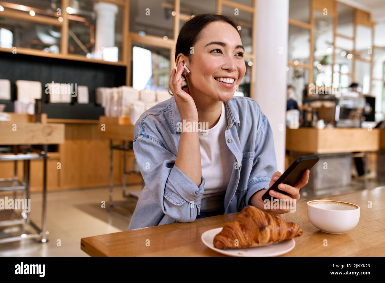 Junge lächelnde asiatische Frau Student mit Smartphone hören Podcast. Stockfoto