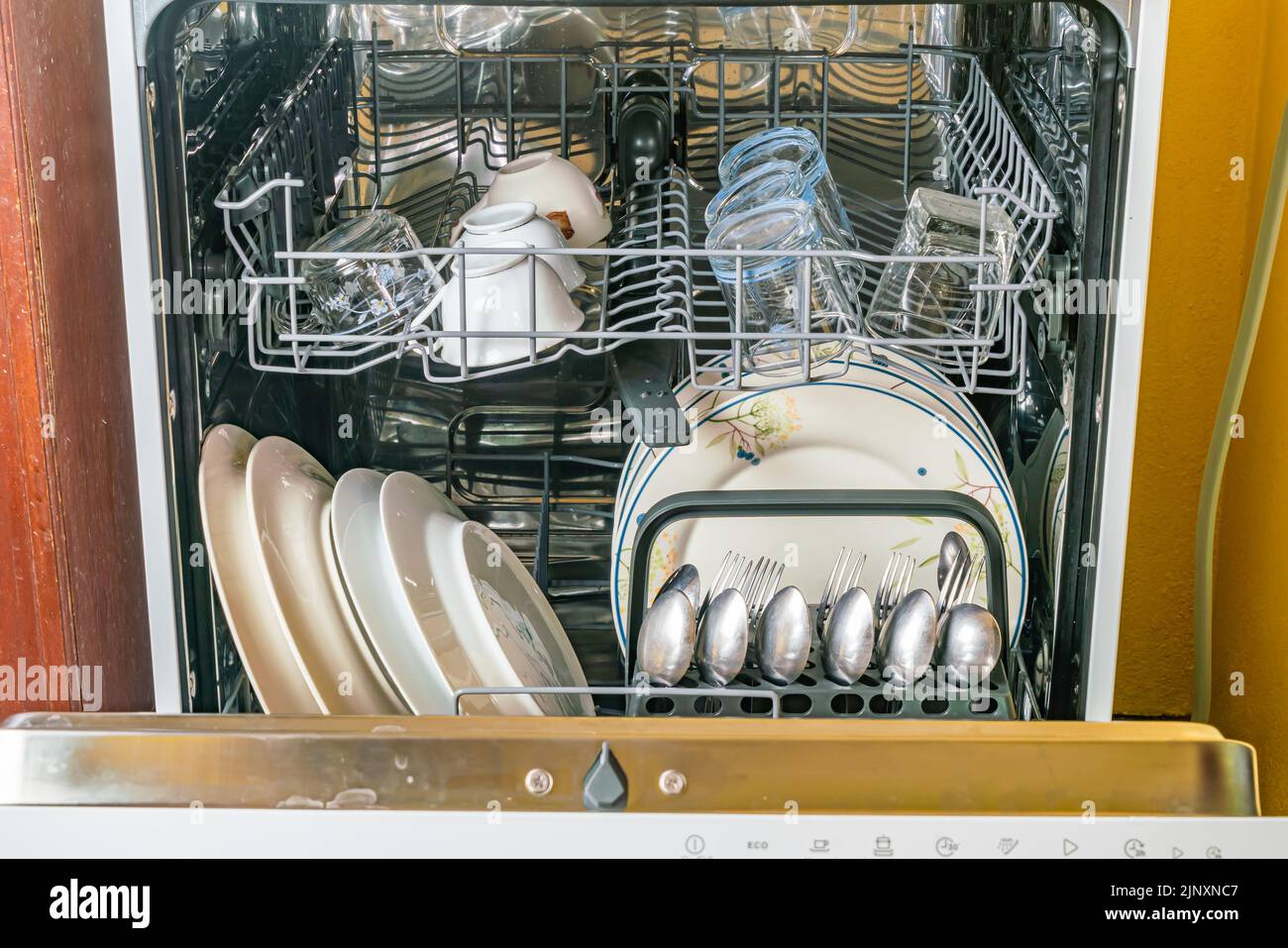 Vorderansicht des geöffneten Geschirrspülers mit sauberem Geschirr, Gläsern und anderen Küchenutensilien nach der Reinigung. Stockfoto