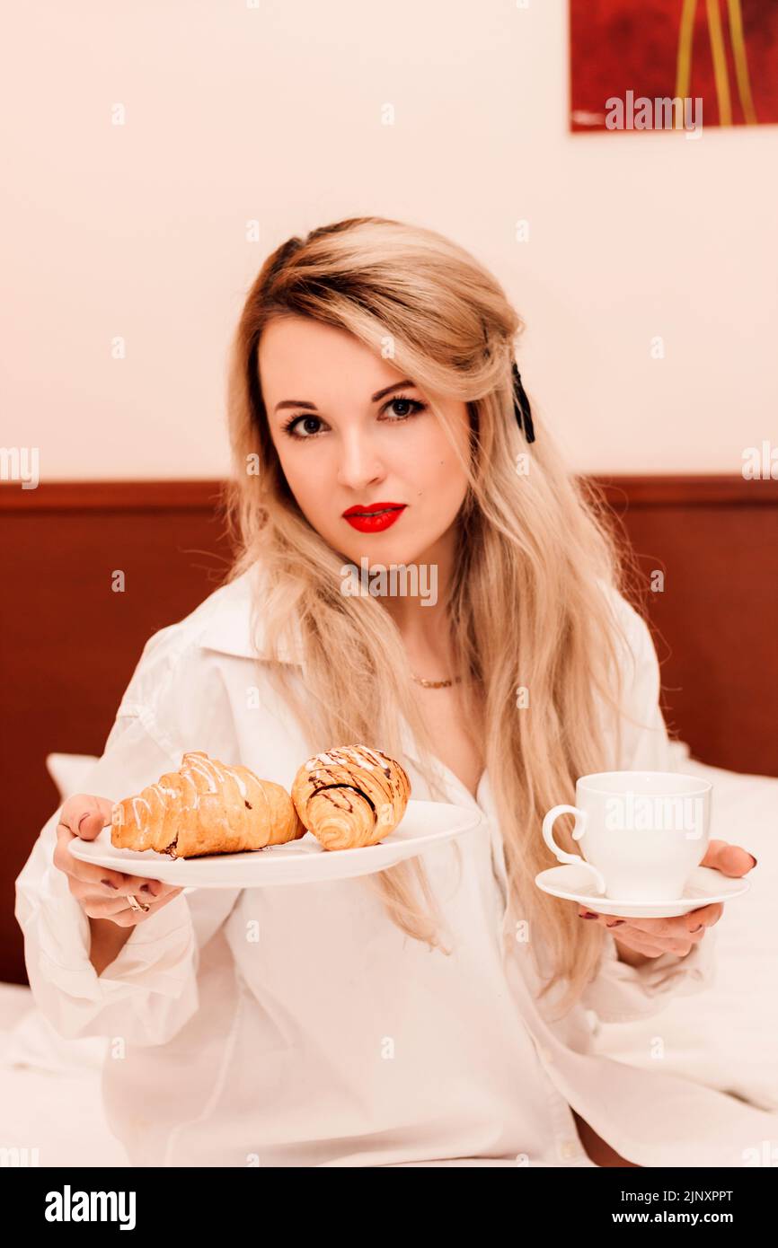 Frühstück im Bett. Eine junge, schöne Frau frühstückt im Bett. Stockfoto