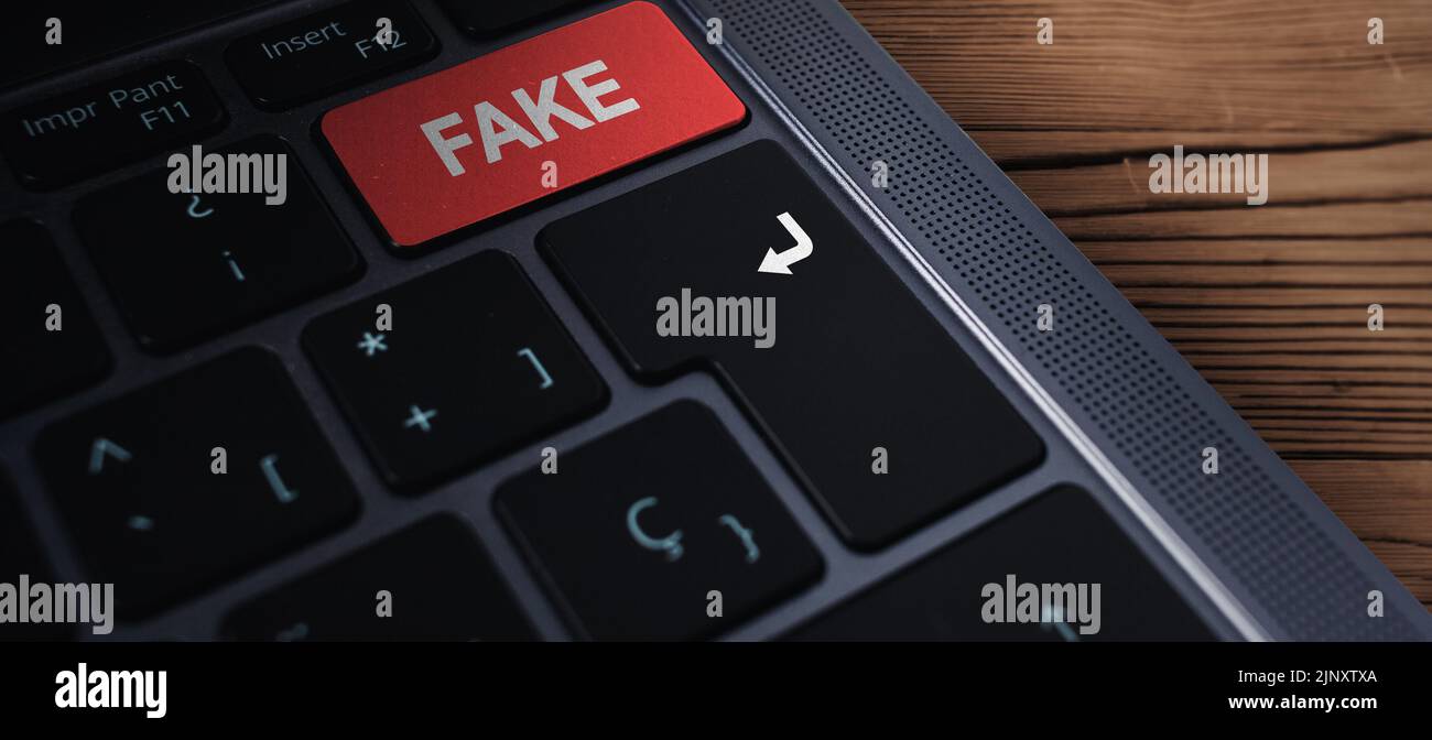 Banner-Nahaufnahme der Laptop-Tastatur mit „gefälschtem“ Text auf der Taste und selektivem Fokus. Roter Knopf mit gefälschtem Text darauf. Fake News Konzept. Stockfoto
