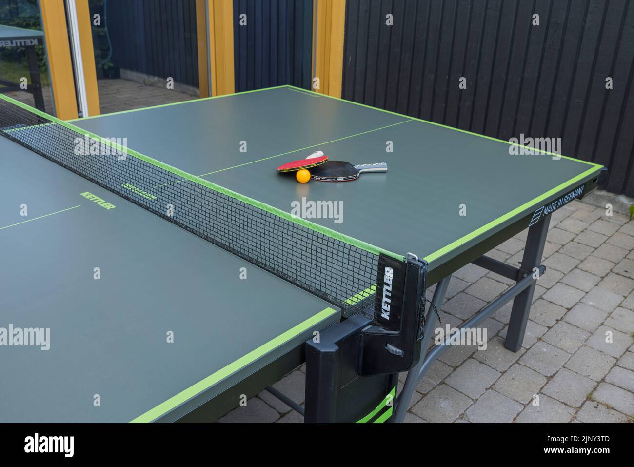 Blick auf die Tischtennisplatte mit Schlägern und Ball im Innenhof des Privathauses. Schweden. Uppsals. Stockfoto