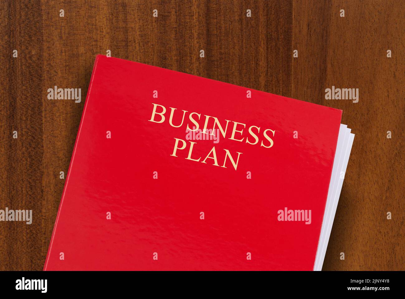 Roter Ordner auf dem Schreibtisch mit dem Titel Business Plan. Aufnahme aus dem oben genannten Geschäftskonzept Stockfoto