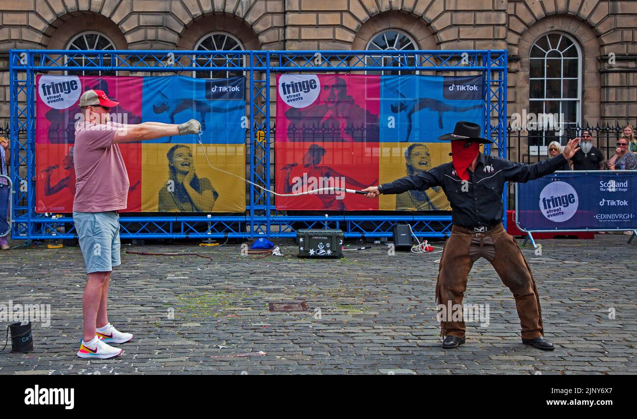 EdFringe 10. Day, Edinburgh, Schottland, Großbritannien. Straßenkünstler, die auf und abseits der Royal Mile ein anständiges Publikum erreichen. Im Bild: Der entscheidende Moment, in dem der Straßenkünstler Todd 'The Cowboy' mit verbundenen Augen ein Stück Zeitung in zwei Hälften zerreißt, das in den Händen eines mutigen Freiwilligen gehalten wird.Quelle: ArchWhite/alamy Live News. Stockfoto