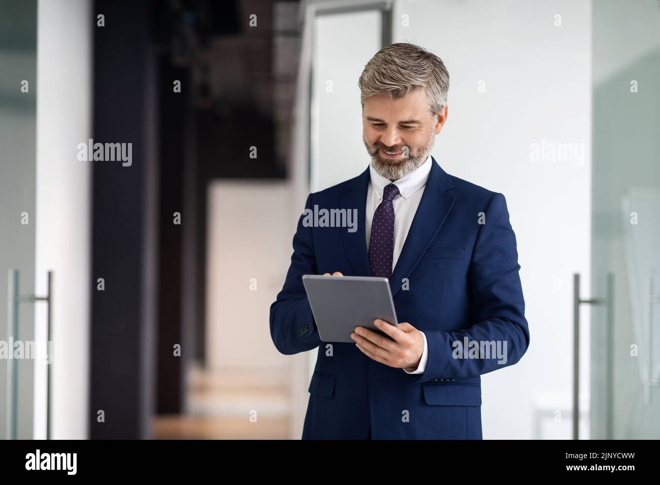 Modernes Technologiekonzept. Lächelnder, Reifer Geschäftsmann Trägt Anzug Mit Digitalem Tablet Im Innen-Bereich Stockfoto