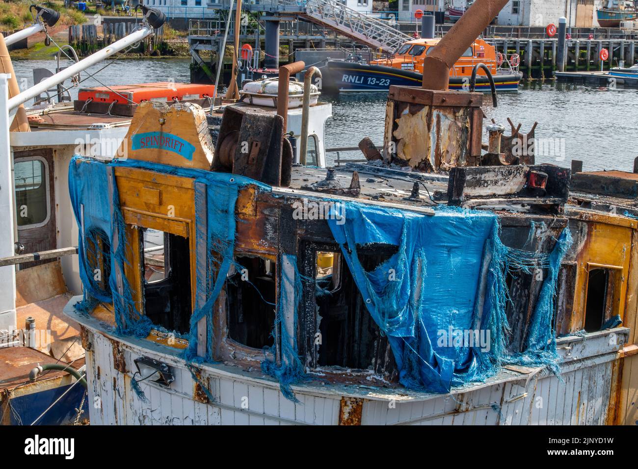 Schiffswrack eines alten Fischtrawlers mit kaputten Fenstern und einer Plane, die sich über das Steuerhausdach erstreckte, um das Wetter zu verhindern. Stockfoto