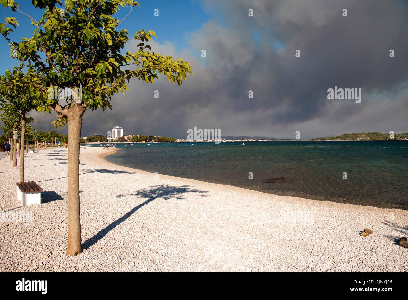 Zadar, Kroatien - Juli, 13. 2022: Leerer Strand und Rauch vom Sommerwildfeuer, das näher an die Stadt heranzunähern. Stockfoto