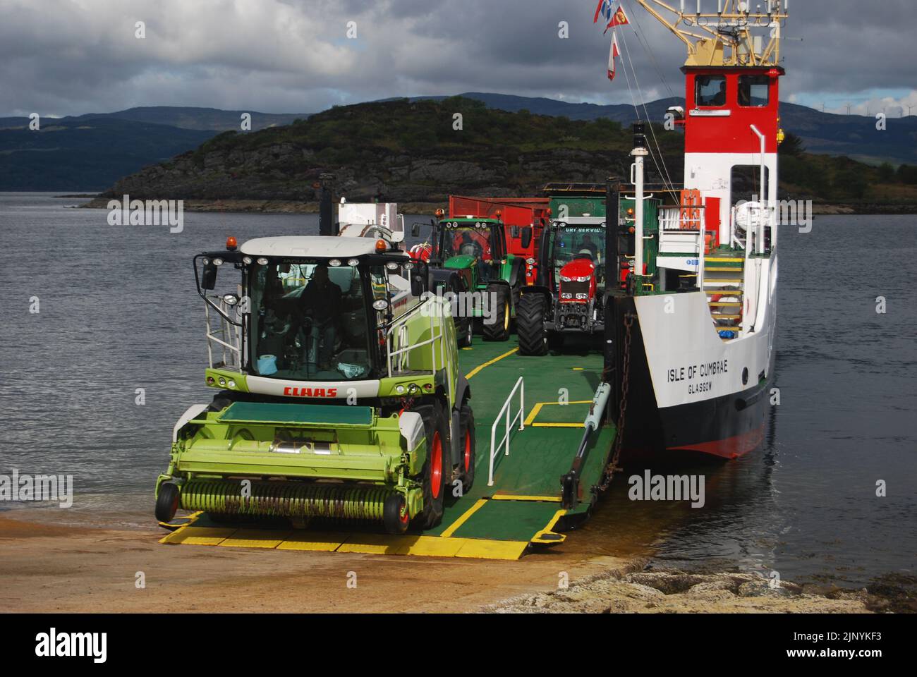 Ein Feldhäcksler, Traktoren und Anhänger verlassen die „MV Isle of Cumbrae“ Tarbert zur Portavadie CalMac Fähre auf Loch Fyne, Argyll, Schottland, Großbritannien. Stockfoto
