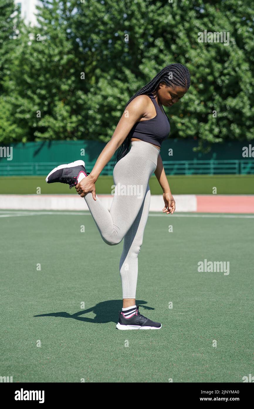 Afroamerikanische Frau versucht, auf dem linken Bein stehende Gesäßmuskeln auf grünen Rasenboden zu Pumpen Stockfoto