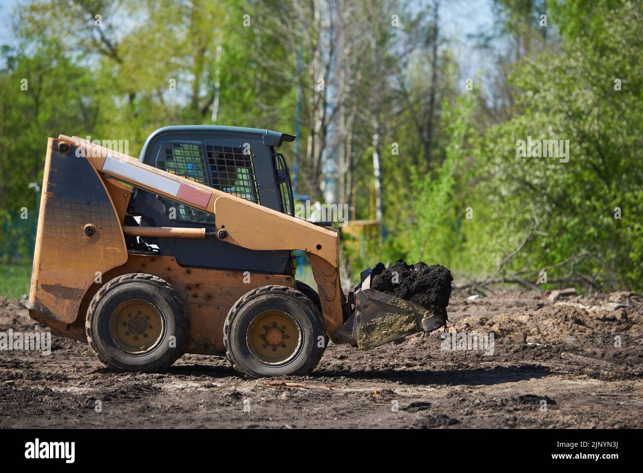 Mini-Radbagger arbeitet im Garten, transportiert Boden Stockfoto