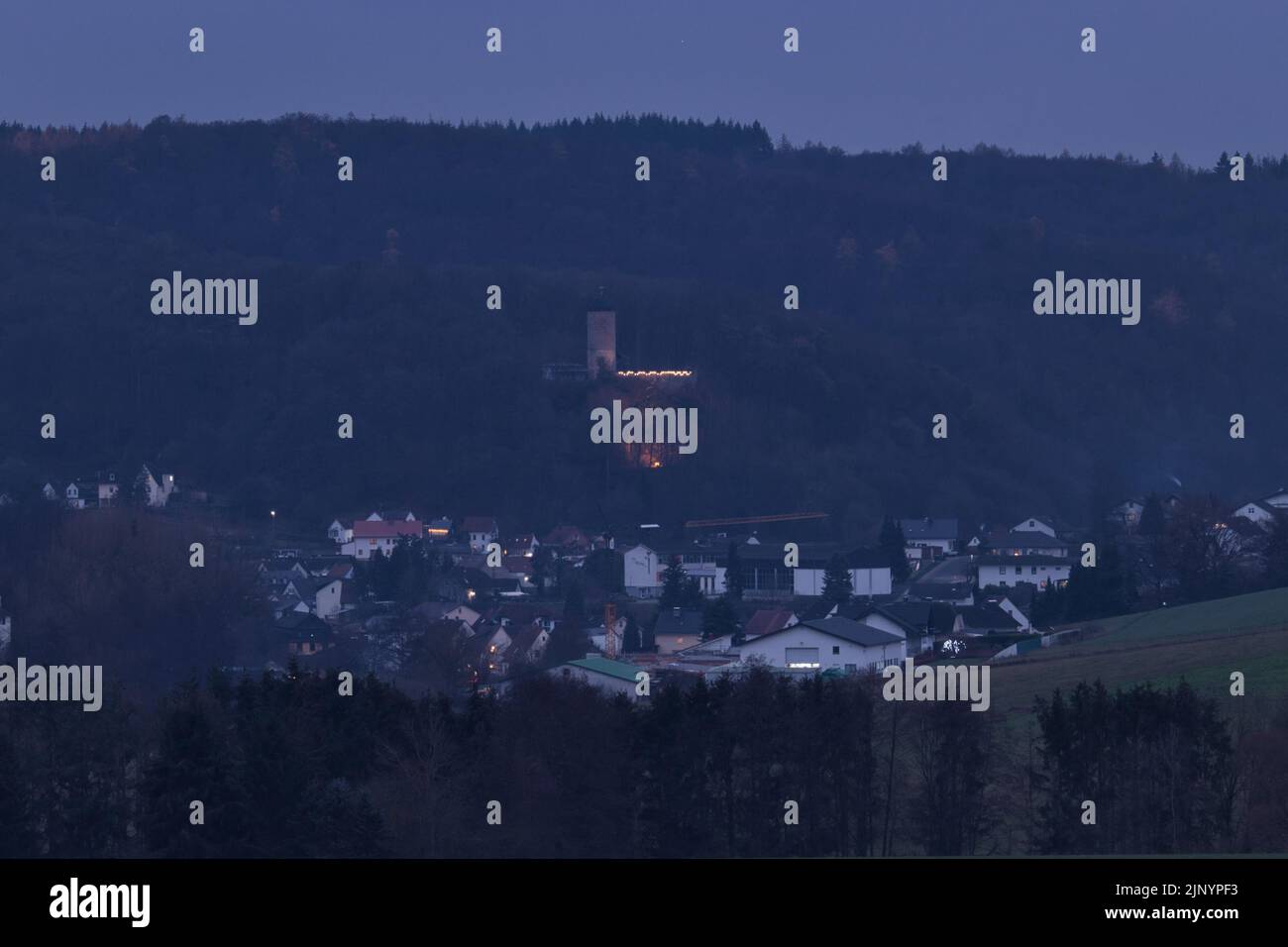 Braunfels, Deutschland - 9. Dezember 2020: Burg Philippstein leuchtet nachts auf einem Hügel über einem kleinen Dorf in Deutschland. Stockfoto