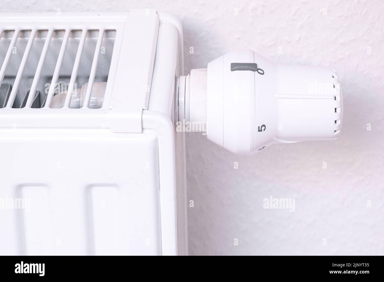 Der Temperaturregler des Heizkörpers der Wasserheizung im Wohnzimmer. Nahaufnahme. Weiße Heizbatterie. Stockfoto