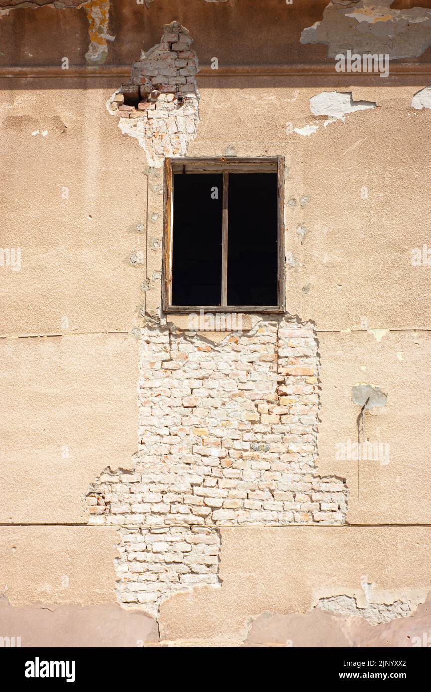Das Äußere des alten zerfallenden Gebäudes hat ein einziges Fenster, das Sie mit einem Holzrahmen sehen können, der möglicherweise Glas hat. Dies ist eine Nahaufnahme. Stockfoto