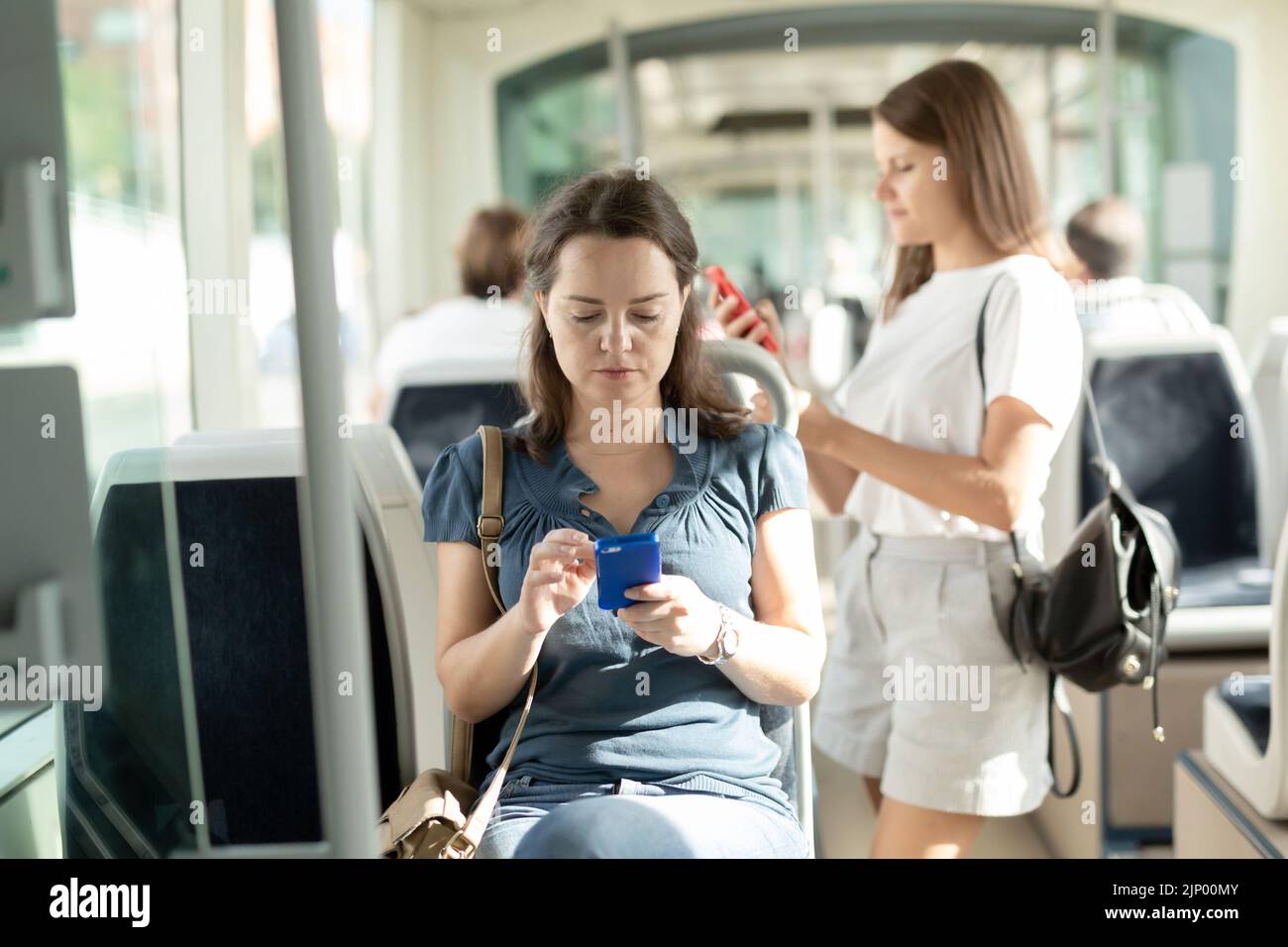 Positive Frau lesen vom Mobiltelefon in der Kabine von Bus oder Straßenbahn Stockfoto