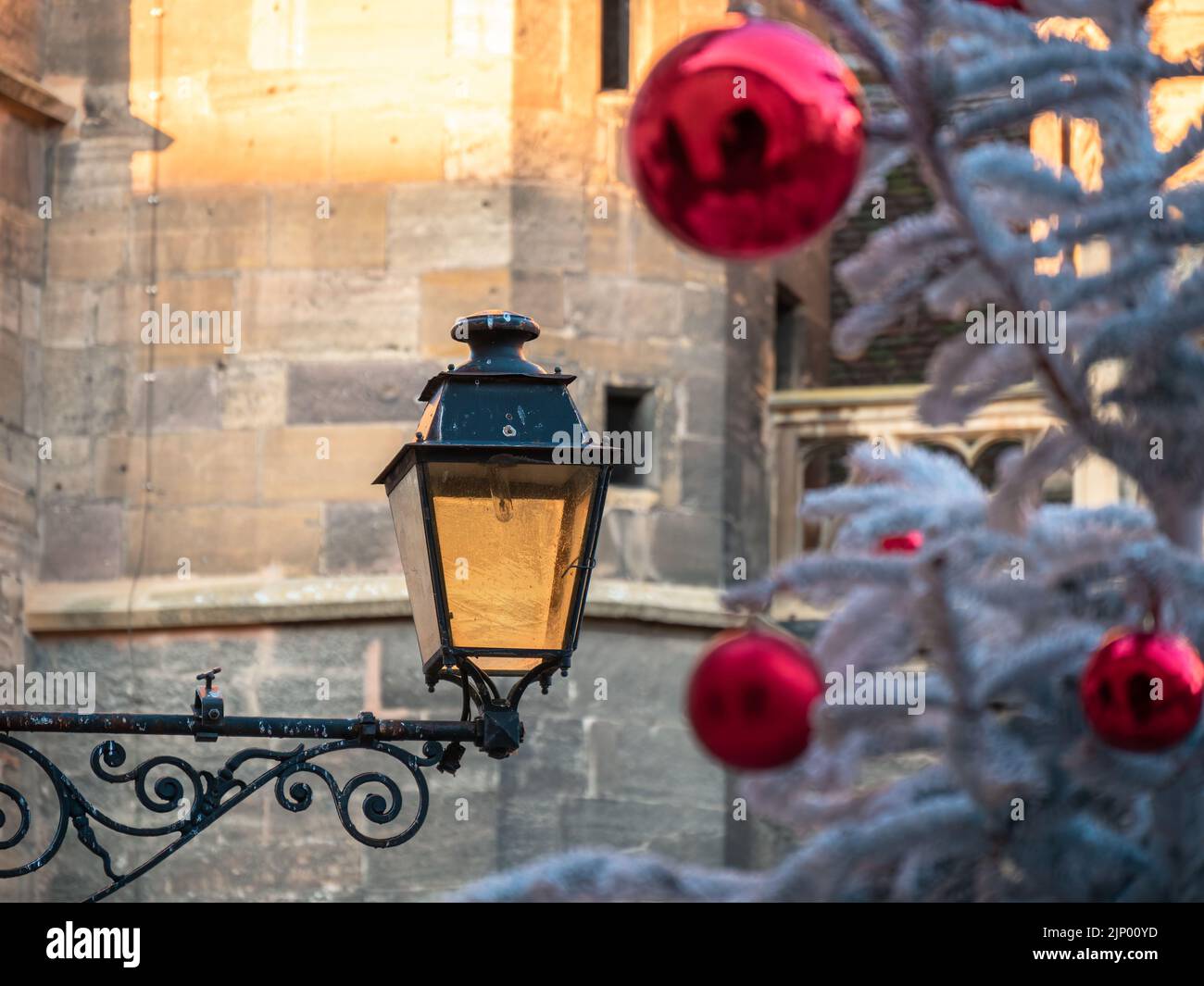 Eine alte Straßenlaterne in Colmar und ein Weihnachtsbaum, der mit roten Ballons geschmückt ist Stockfoto