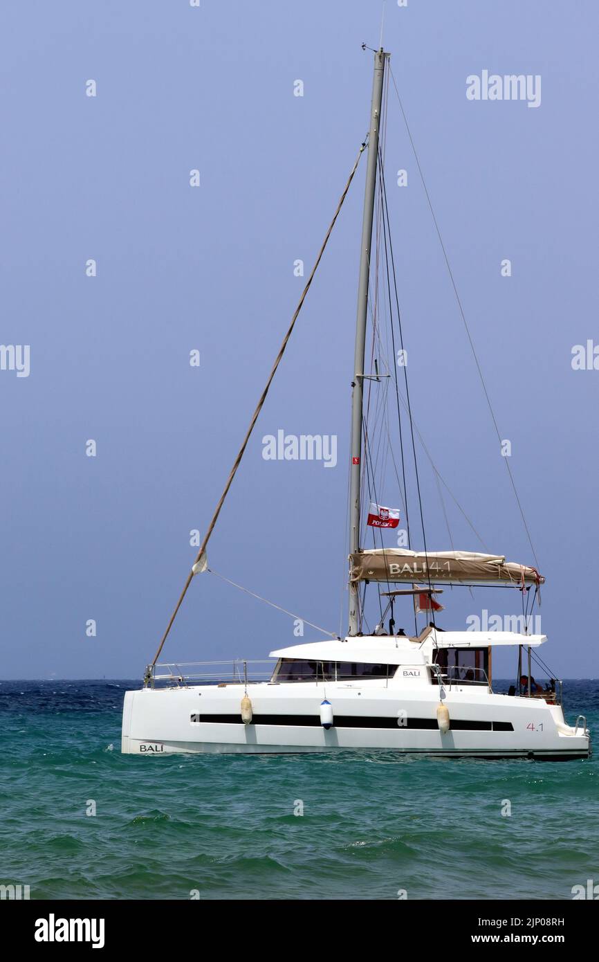 Gäste entspannen sich an Bord eines Bali 4,1 Luxus-Katamarans, der in Ramla Bay, Gozo, Malta, vor Anker liegt. Stockfoto