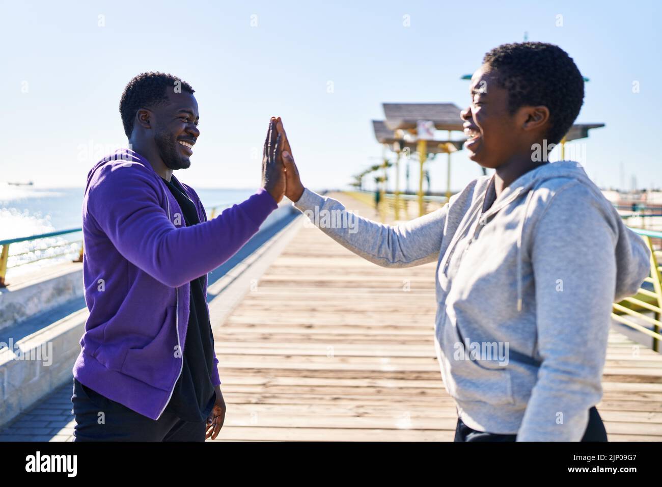 Mann und Frau tragen Sportkleidung mit hohen fünf Händen am Meer angehoben Stockfoto