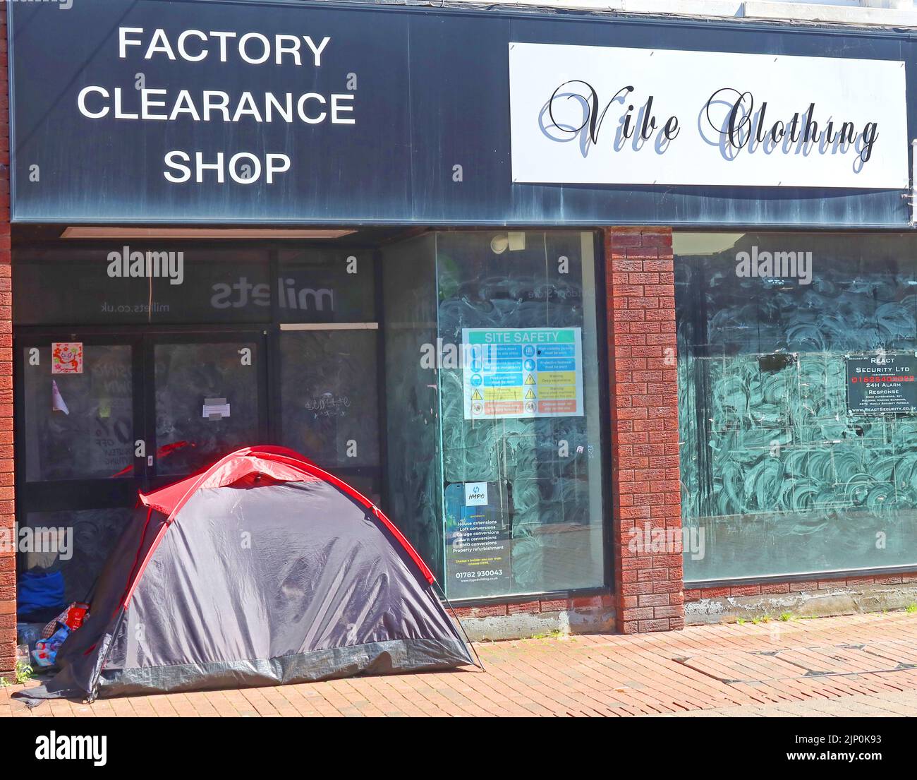 Eine verlassene geschlossene Modehauserei, mit Obdachlosenschlafplatz, mit Zelt im Ladeneingang, Mill Street, Macclesfield, Heshire, England Stockfoto