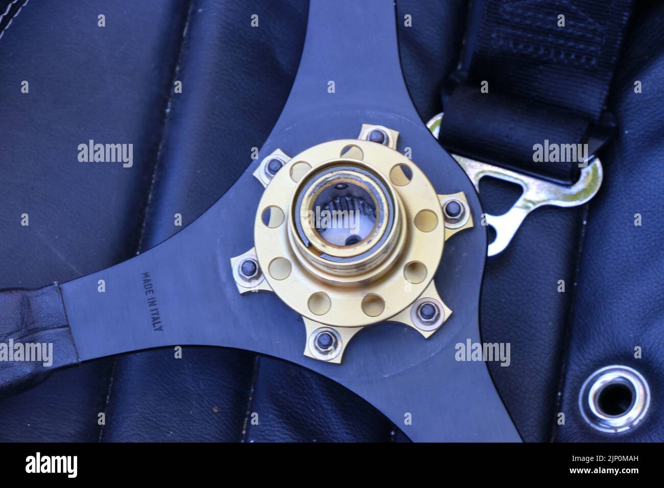 Die Metallnabe eines Lenkrads steht im Kontrast zum dunkelblauen Innenraum eines antiken Autos. Stockfoto