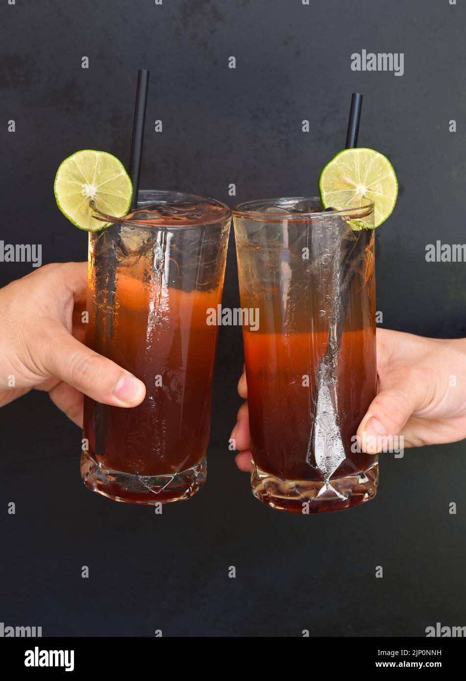 Hände klirrende Gläser mit Pflaumenwein Cocktails auf schwarzem Hintergrund Stockfoto