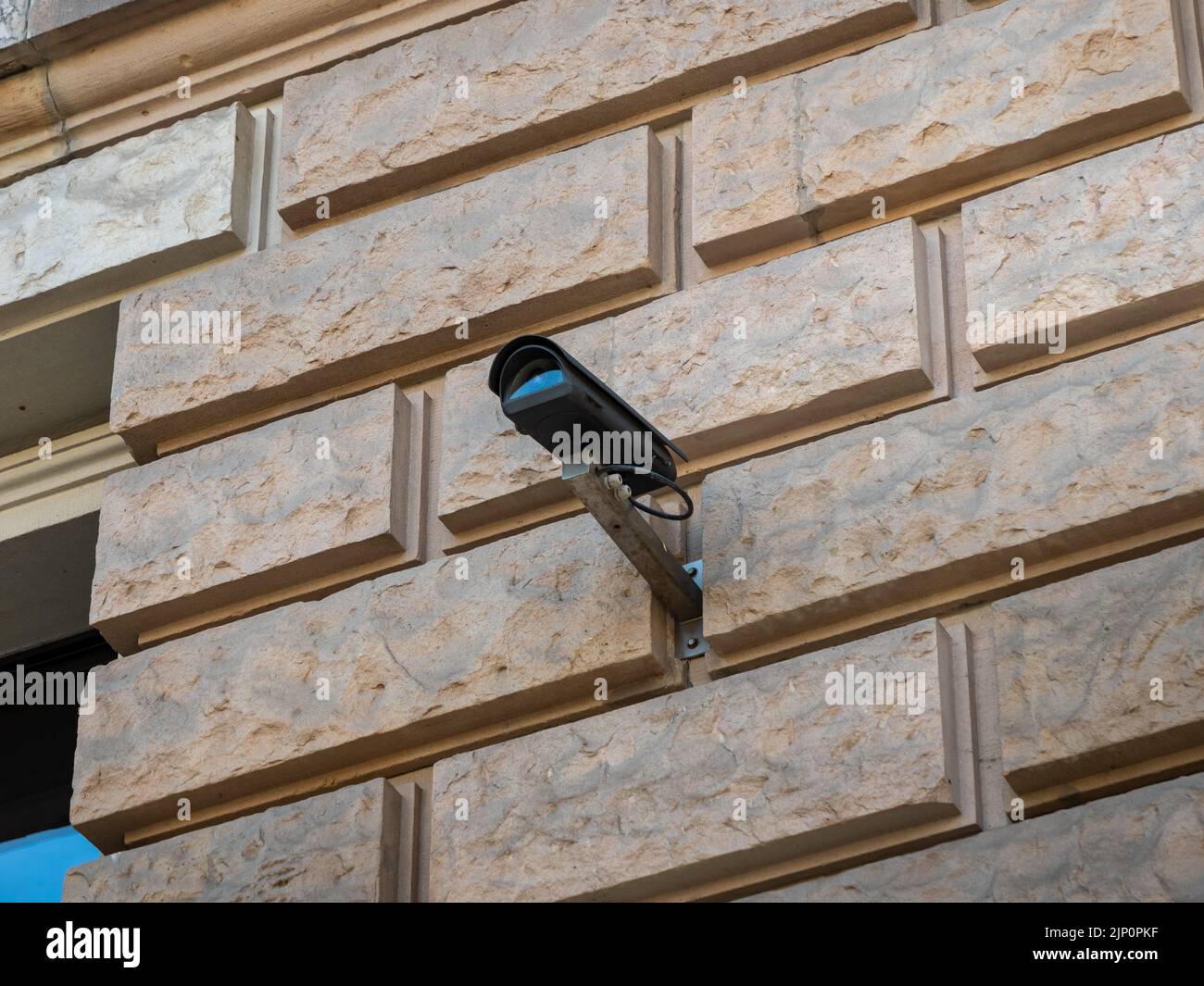 Videoüberwachung in einem öffentlichen Bereich. CCTV-Kamera, die an einer Außenwand eines Regierungsgebäudes montiert ist. Eine schwarze Videokamera zeigt irgendwo hin. Stockfoto