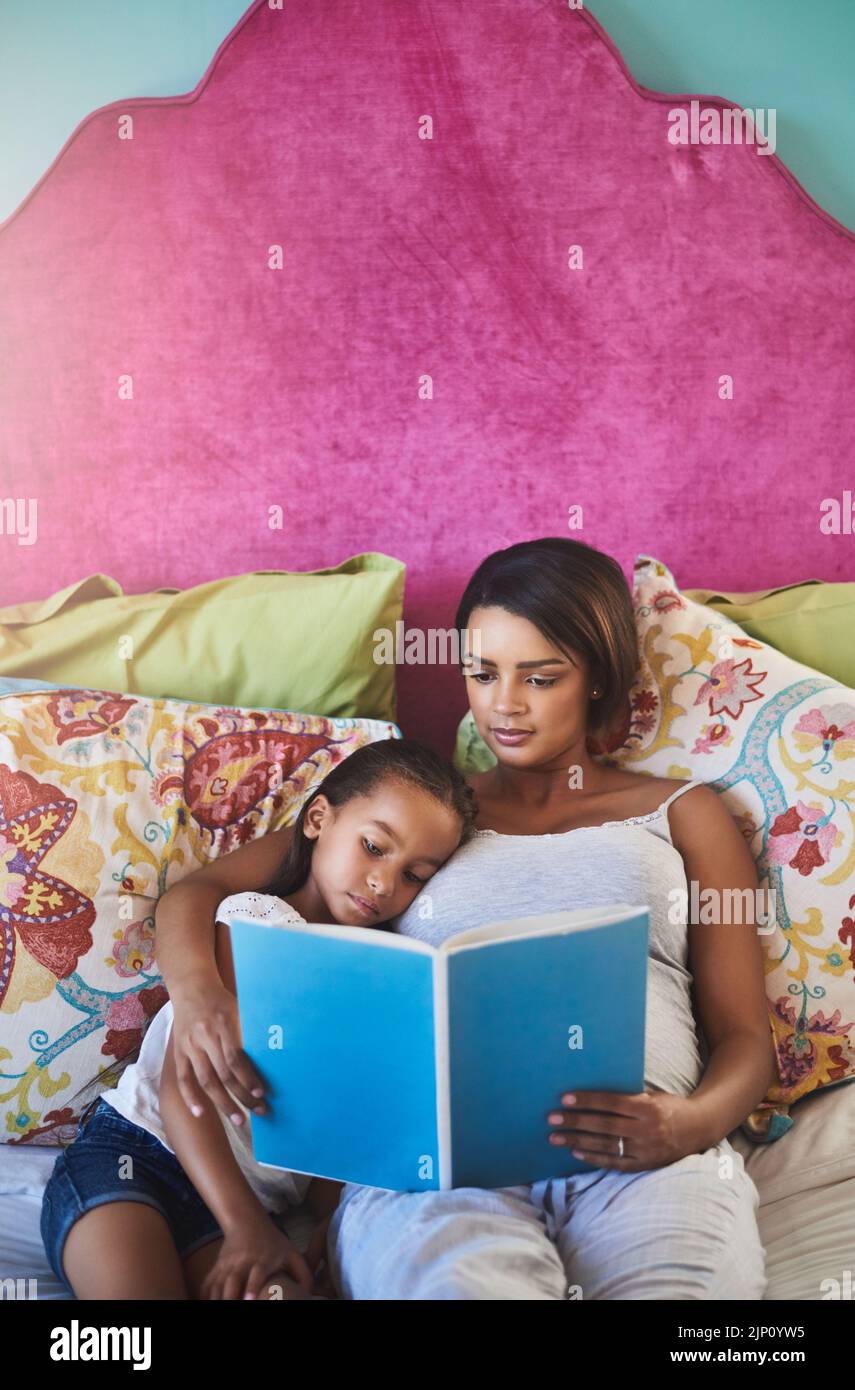 Lesen bringt Licht in die kindeigene Phantasie. Eine Mutter liest ihrer kleinen Tochter zu Hause eine Geschichte vor. Stockfoto