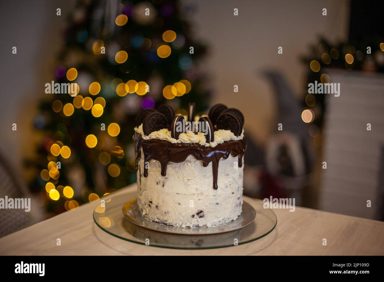 Kuchen mit schwarzen Plätzchen und mit unscharfem christbaumhintergrund Stockfoto