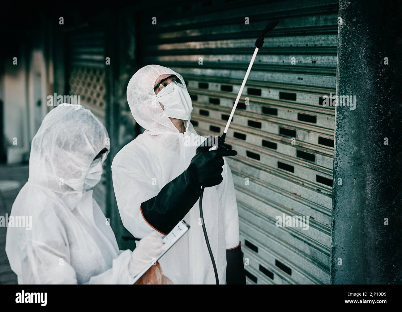Medizinisches Personal desinfiziert ein Gebäude während der covid Pandemie oder reinigt es, um die Ausbreitung von Infektionen zu verhindern. Spezialisten sprühen Desinfektionsmittel Stockfoto