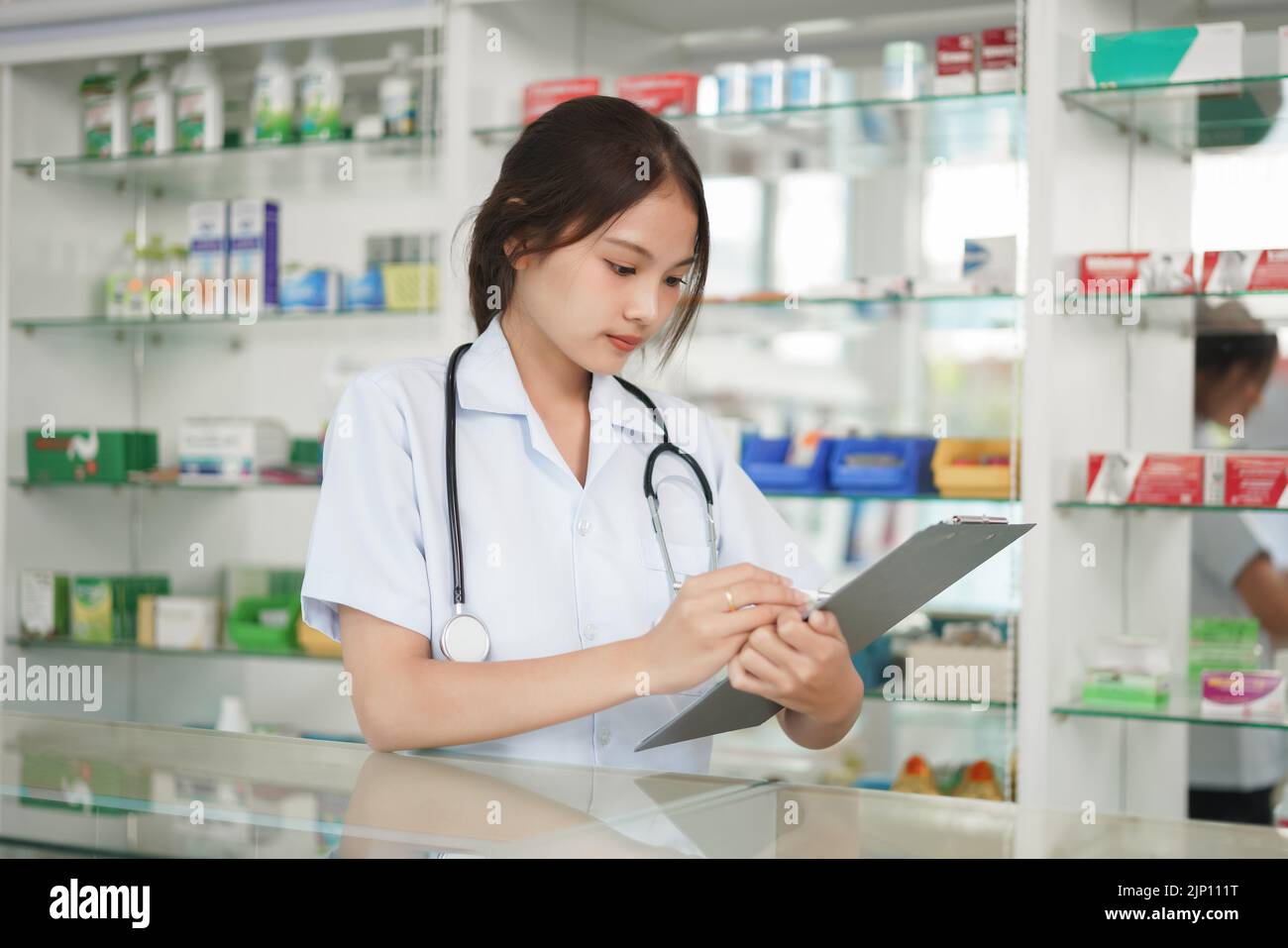 Medizin und Gesundheitskonzept, Apothekerin schreibt Rezept und medizinische Eigenschaften. Stockfoto