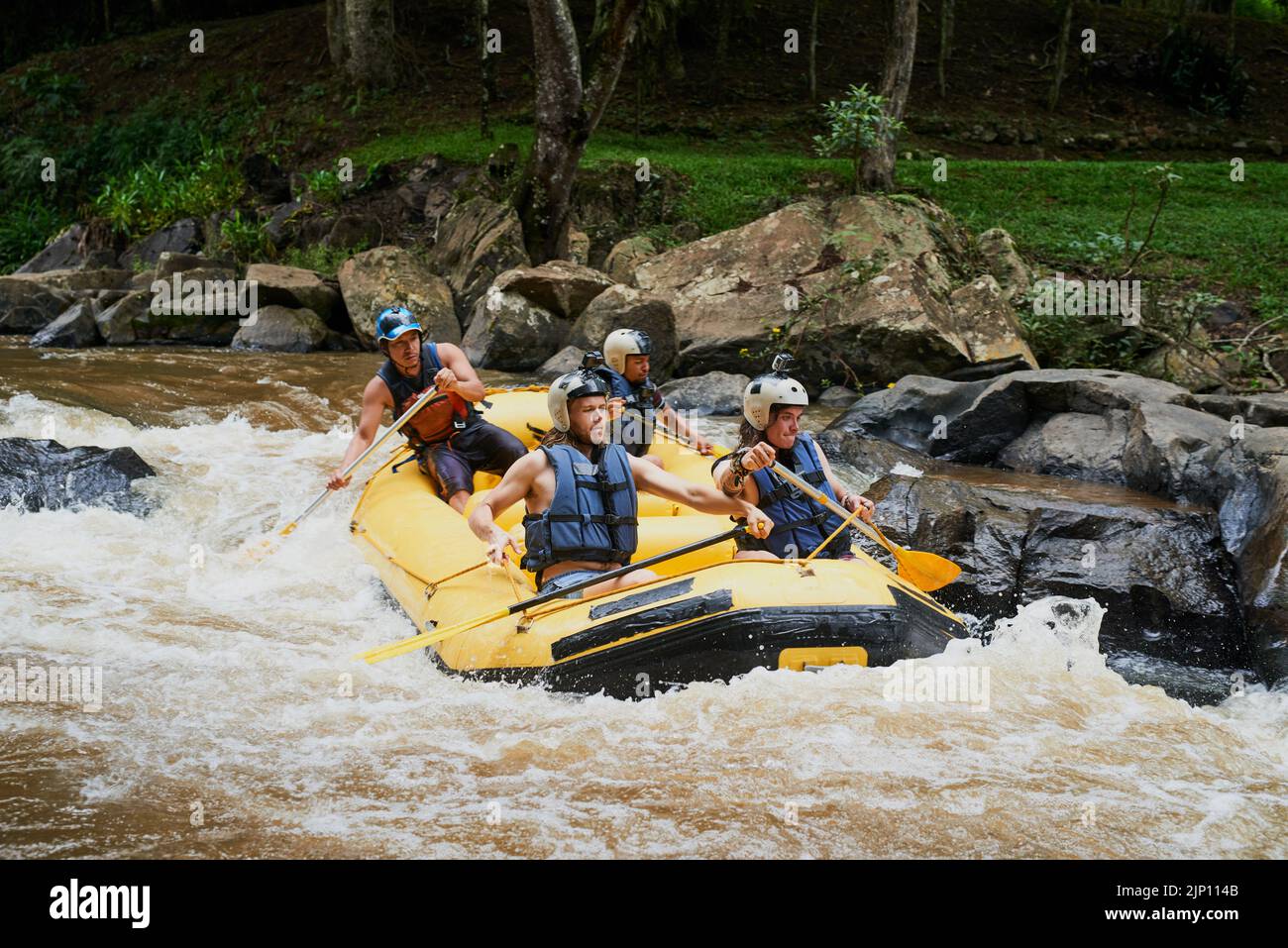 Die Stromschnellen sind lebhaft, aber sie genießen die Herausforderung. Eine Gruppe junger männlicher Freunde Wildwasser-Rafting. Stockfoto
