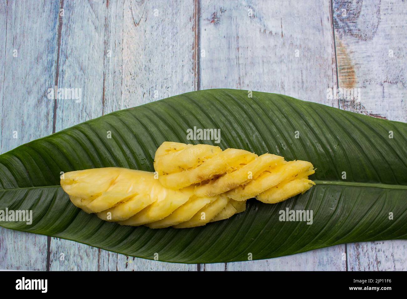 Zwei in Scheiben geschnittene gelbe Ananas auf Blatt serviert Stockfoto