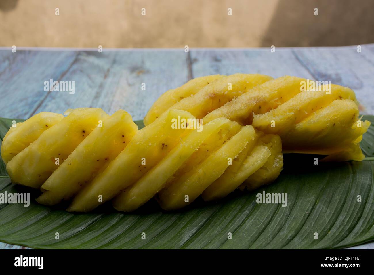 Zwei in Scheiben geschnittene gelbe Ananas auf Blatt serviert Stockfoto