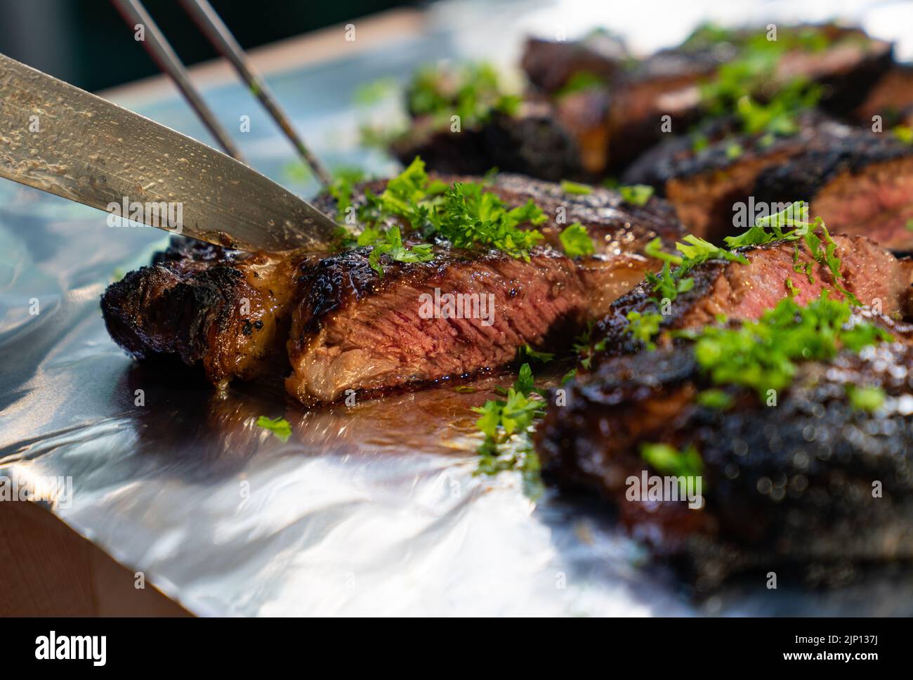 Nahaufnahme des auf einer Aluminiumfolie geschnittenen, kohlbekohlten Steaks Stockfoto