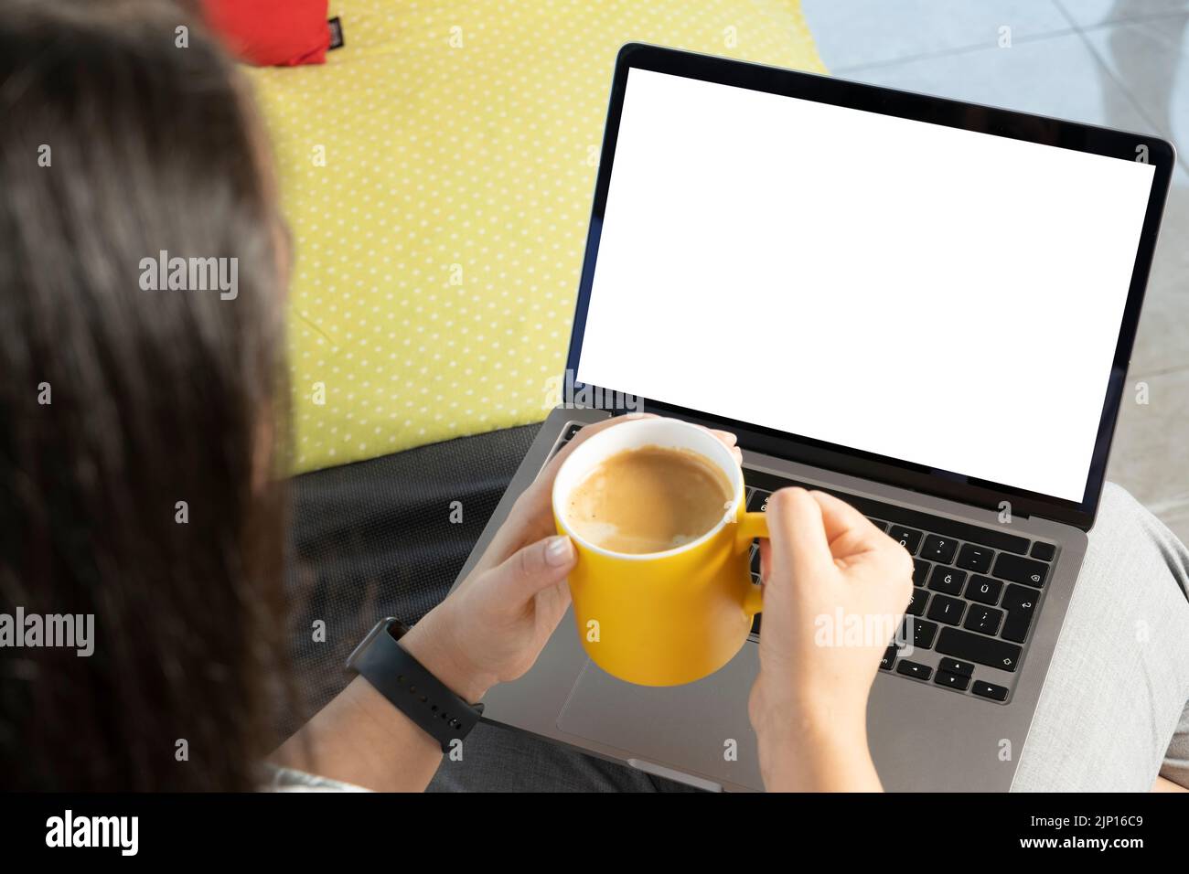 Laptop in der Hand, junge kaukasische Frau in der Hand. Trinken Sie frischen Kaffee und schauen Sie sich den weißen Computerbildschirm an. Entspannen beim Ansehen von Filmen. Stockfoto