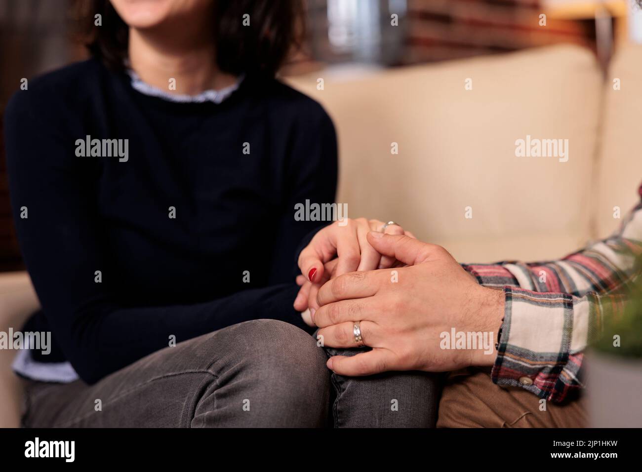 Ehemann und Ehefrau halten sich die Hände, nachdem sie den Ehekonflikt mit Hilfe des Couselors bei der Therapiesitzung gelöst haben. Glückliches Paar, das sich bei der Beziehungsabstimmung im Amt wohlfühlt. Stockfoto