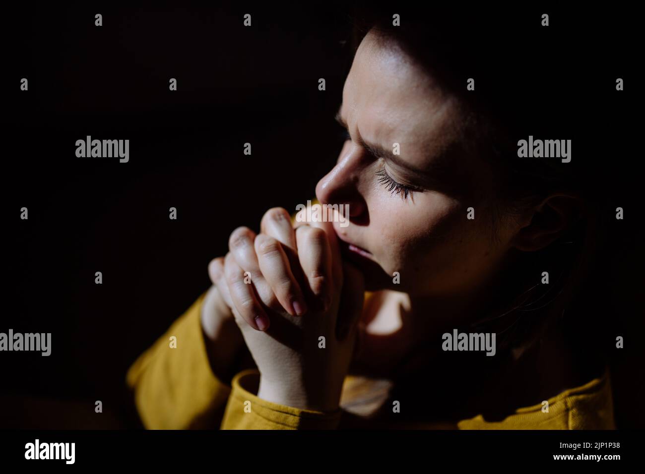 Traurige Frau, die den Segen der Hand hält und betet, sich niedergeschlagen fühlt, um Hilfe bittet. Spiritualität, Religion konzeptioniert auf schwarzem Hintergrund. Stockfoto