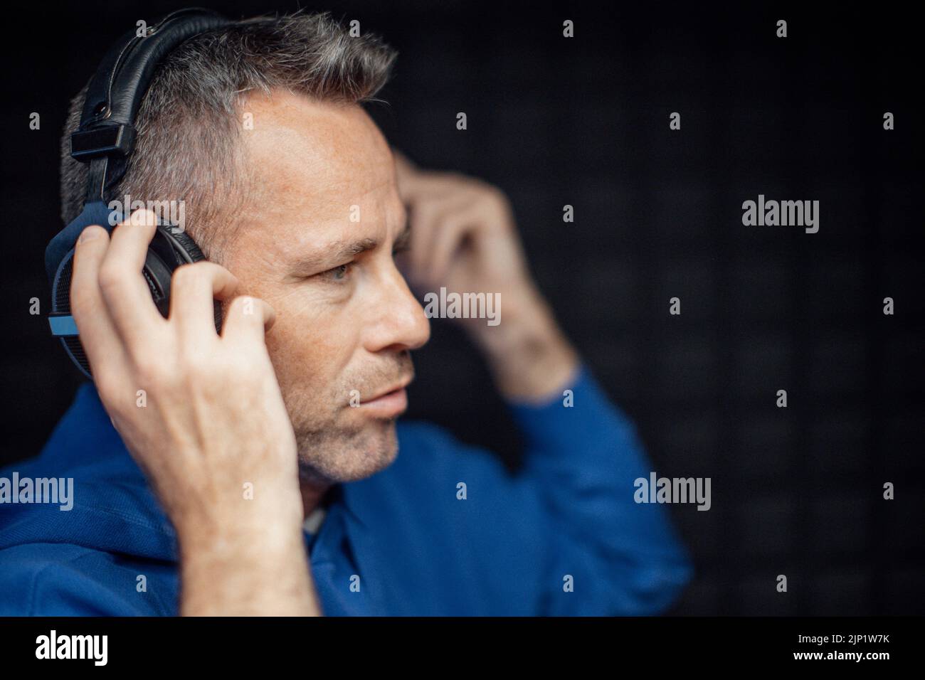 Portrait eines reifen Radiohosts, der während des Podcasts Kopfhörer aufsetzt Stockfoto