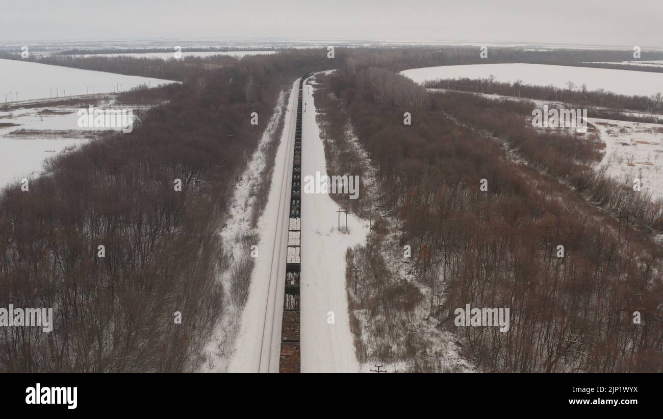 Ein Zug mit offenen Waggons fährt durch das winterliche Russland. Ein Zug mit Waggons transportiert Metall auf Schienen. russischer Zug Winter Stockfoto