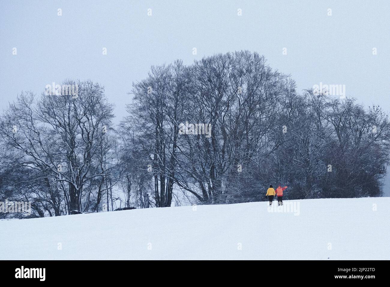 Spazieren Sie an einem winterlichen Tag voller Schnee, 2 Personen mit roten und gelben Jacken laufen im Schnee Stockfoto